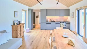 A modern kitchen with grey cabinets, a wooden dining table, and a built-in oven. - Chalet Hochsteiermark (Mariazell)