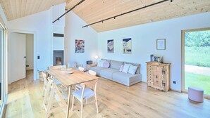 A spacious living area with a wooden floor, a dining table with chairs, a sofa, and a cabinet. - Chalet Hochsteiermark (Mariazell)