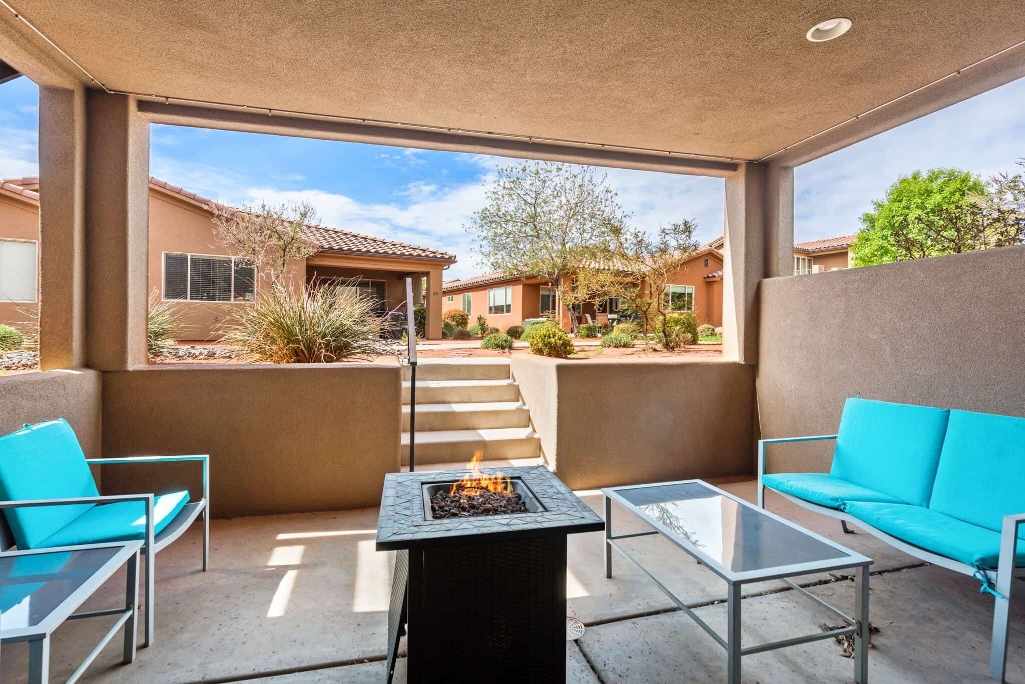 An outdoor patio with a fire pit, seating, and a view of neighboring houses.