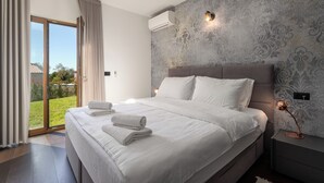 A modern bedroom with a large bed, a sliding glass door to a garden, and a patterned wall. - Villa Casa Veritas with pool for 8 guests, quiet location, near Porec (Višnjan)