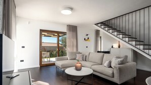A modern living room with a sectional sofa, a round coffee table, and a staircase with a metal railing. - Villa Casa Veritas with pool for 8 guests, quiet location, near Porec (Višnjan)