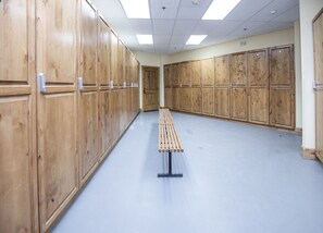Een kleedruimte met houten kasten, een bank en een betegelde vloer.
