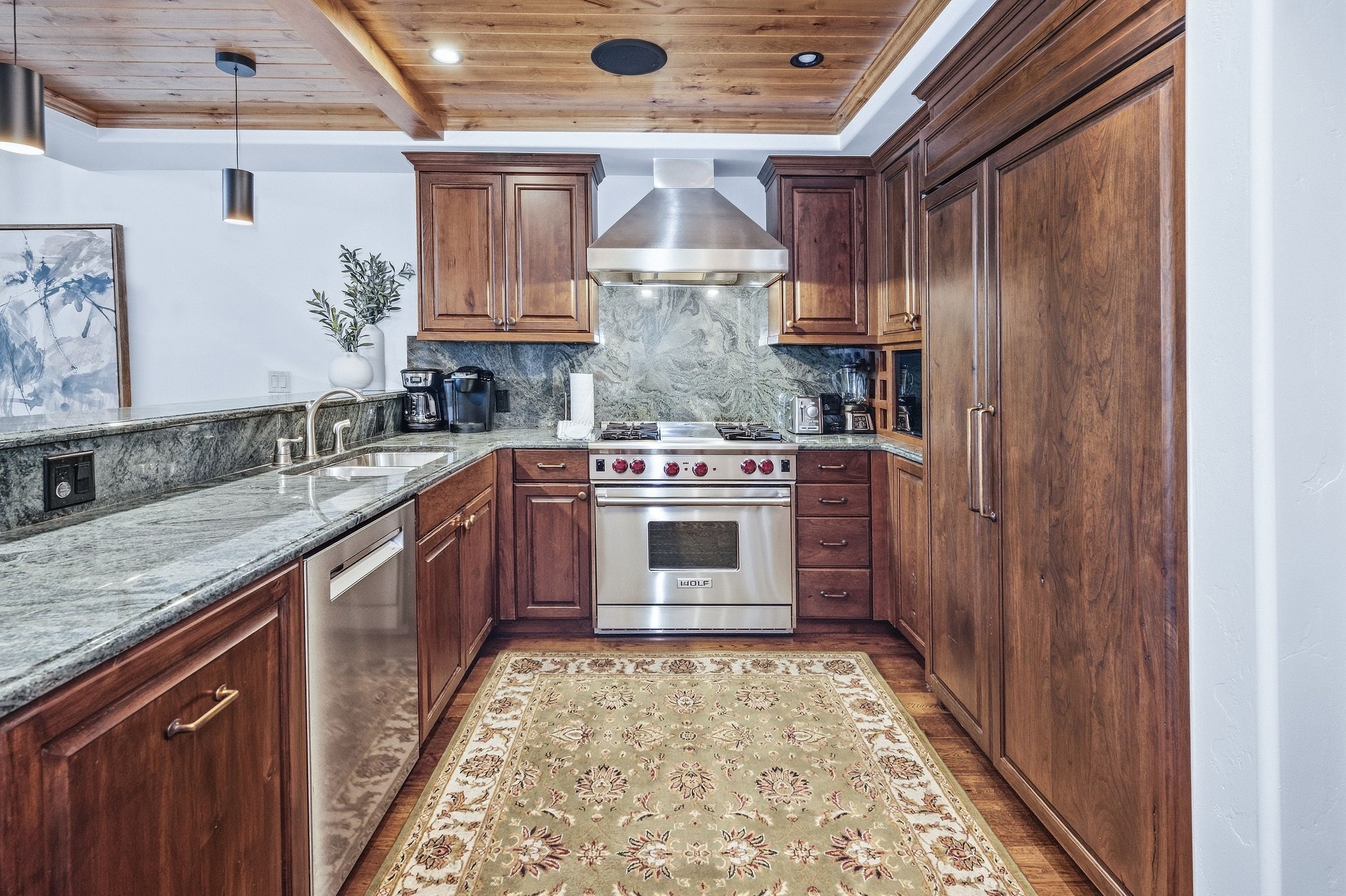 A kitchen with wooden cabinets, a stainless steel range, and a marble countertop.