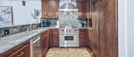 A kitchen with wooden cabinets, a stainless steel range, and a marble countertop.