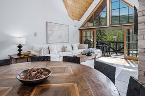 Een moderne woonkamer met een houten salontafel, een witte bank en een groot raam met uitzicht op de omgeving.