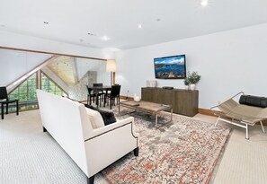 Ein modernes Wohnzimmer mit einem weißen Sofa, einem Couchtisch und einem an der Wand befestigten Fernseher.