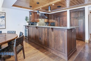 Een ruime keuken met houten kasten, een centraal eiland en een eethoek met een ronde tafel en stoelen.