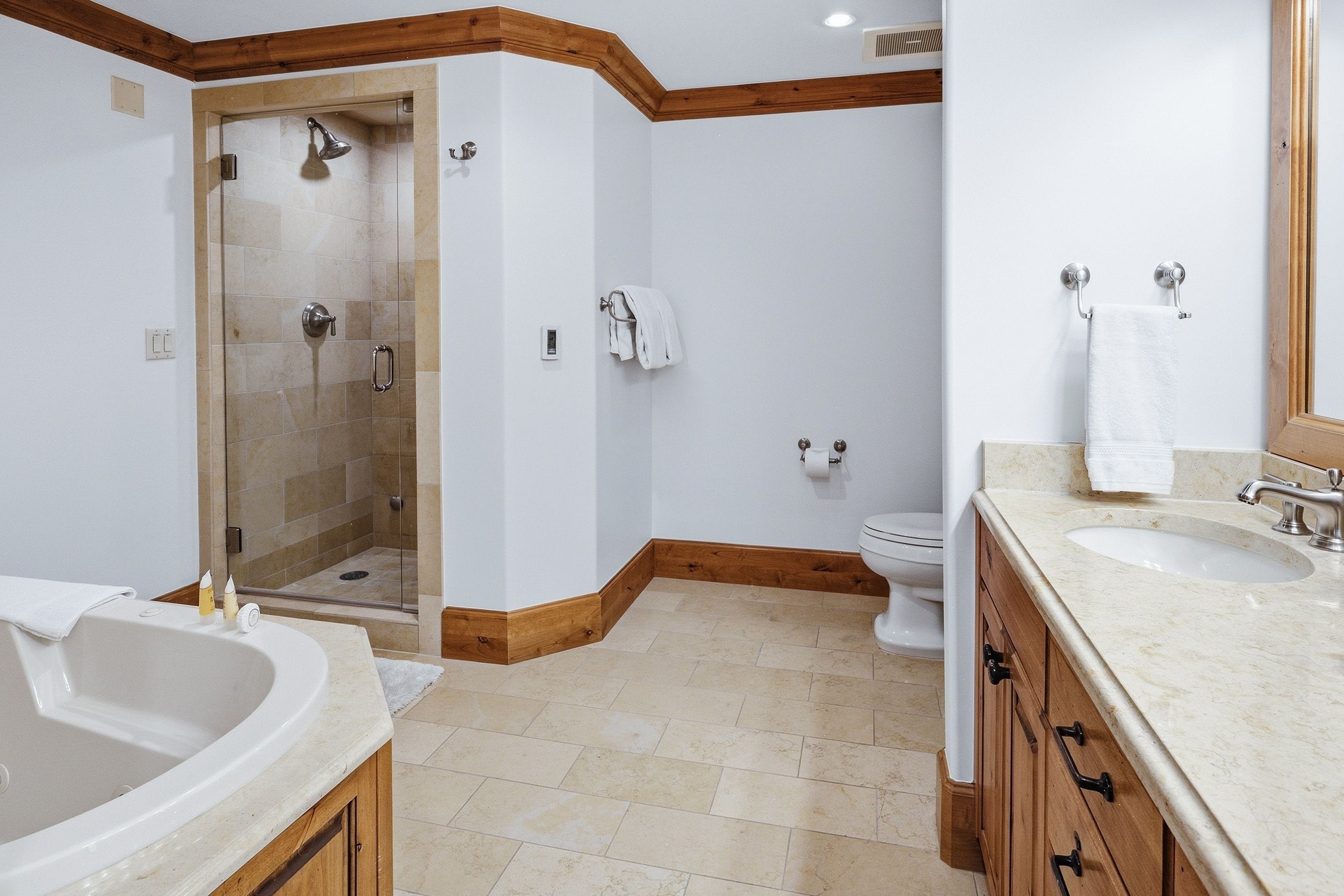 A bathroom with a shower, toilet, sink, and wooden accents.