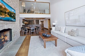 Een ruime woonkamer met een open haard, een eethoek en een bank.
