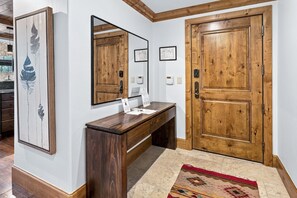 A reception desk with a mirror, wooden doors, and a framed artwork on the wall. - Vail Mountain View #402 4 Bedroom Condo (Vail)