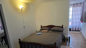 A single bed with a wooden headboard, a bedside table, and a wall-mounted light fixture.