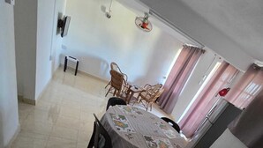 A dining area with a round table covered with a tablecloth, surrounded by chairs.