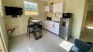 Una cocina compacta con zona de comedor, un refrigerador, un microondas y un televisor.
