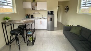 Una cocina compacta con comedor, refrigerador y sofá.