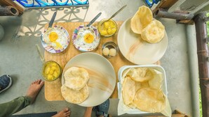 A dining table with plates of food, including eggs and a bowl of mangoes. - Bon Kiputhang (Chungthang)