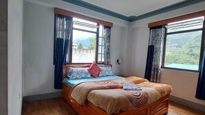 A bedroom with a wooden bed, two windows with curtains, and a view of greenery outside. - Bon Kiputhang (Chungthang)