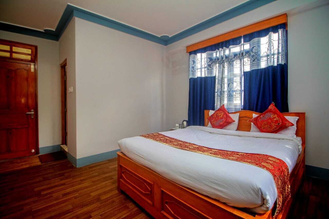 A bedroom with a wooden bed, white bedding, and red pillows.