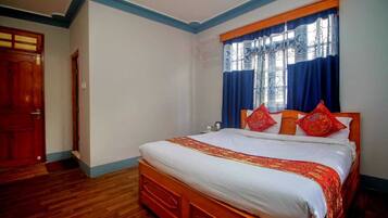 A bedroom with a wooden bed, white bedding, and red pillows.