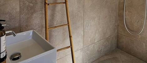 Une salle de bain avec une douche, un lavabo et une échelle en bois.