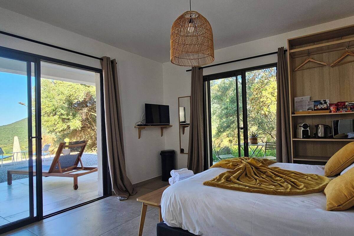 Een slaapkamer met een groot bed, een houten garderobe, een televisie en uitzicht op de omgeving.