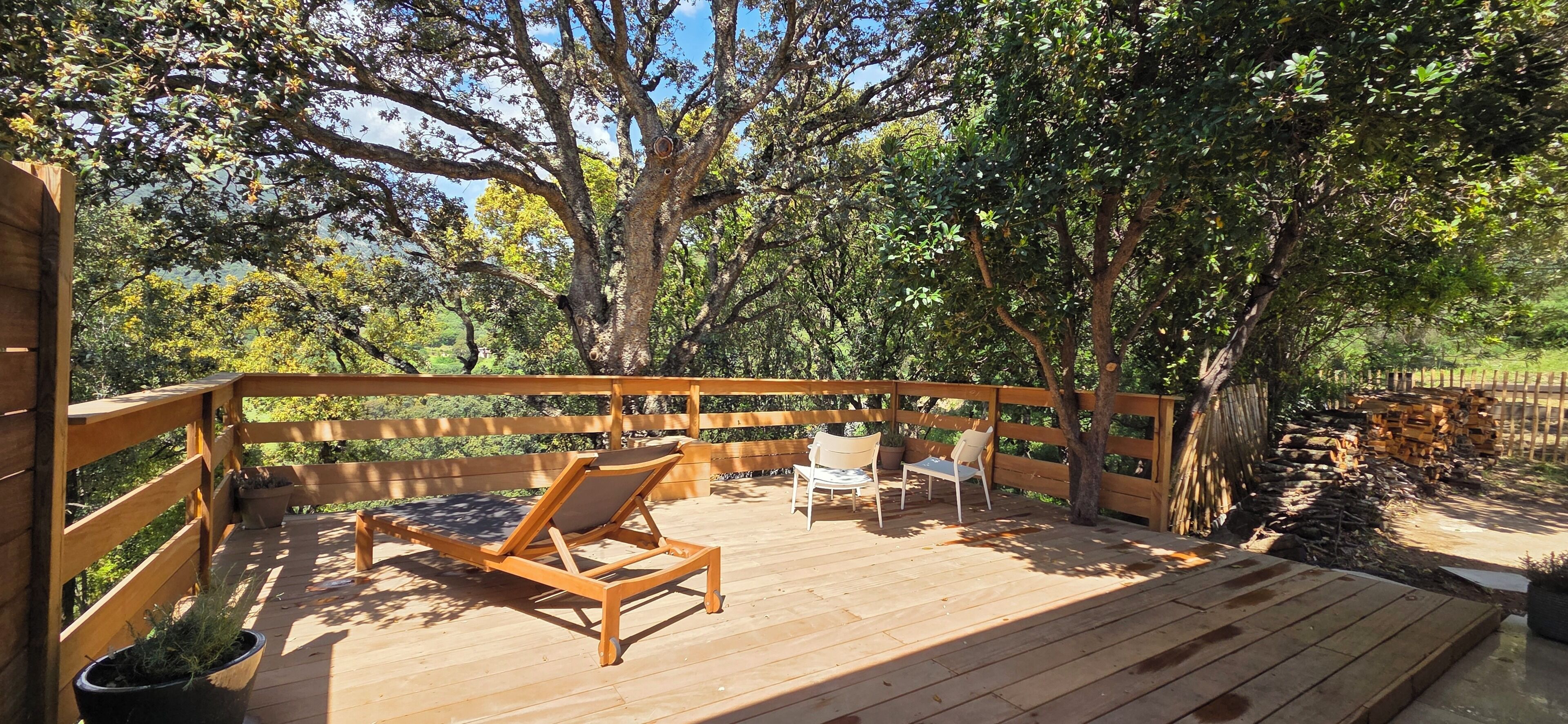 Una terraza de madera con sillas de descanso y una valla de madera.