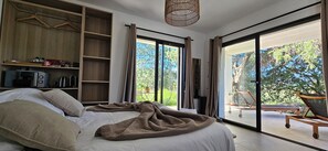 Une chambre à coucher comprenant un lit, une armoire, un bureau et donnant sur l’extérieur.