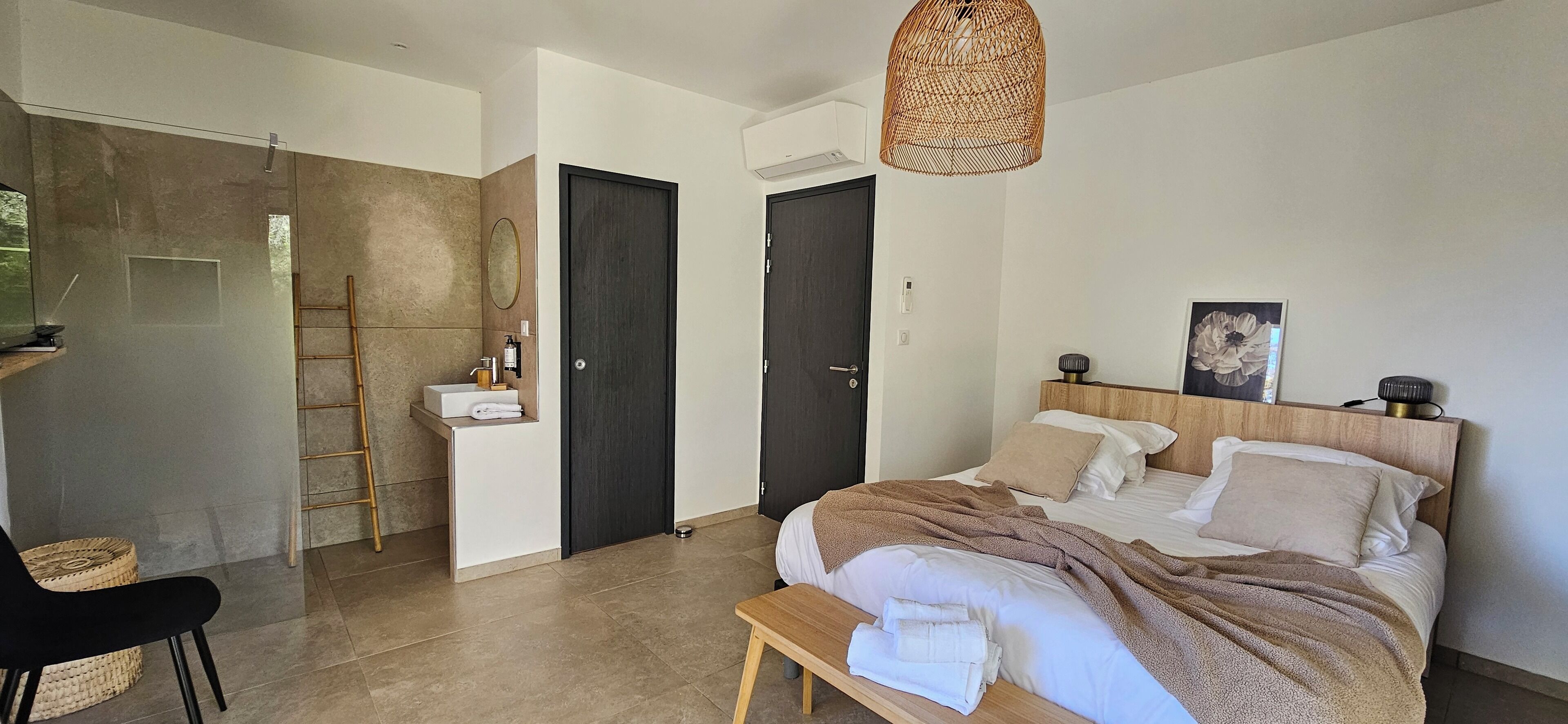 Un dormitorio moderno con cama, mesita de noche y baño con lavabo y espejo.
