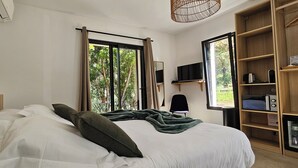Een slaapkamer met een bed, een televisie, een boekenkast en een raam met gordijnen.