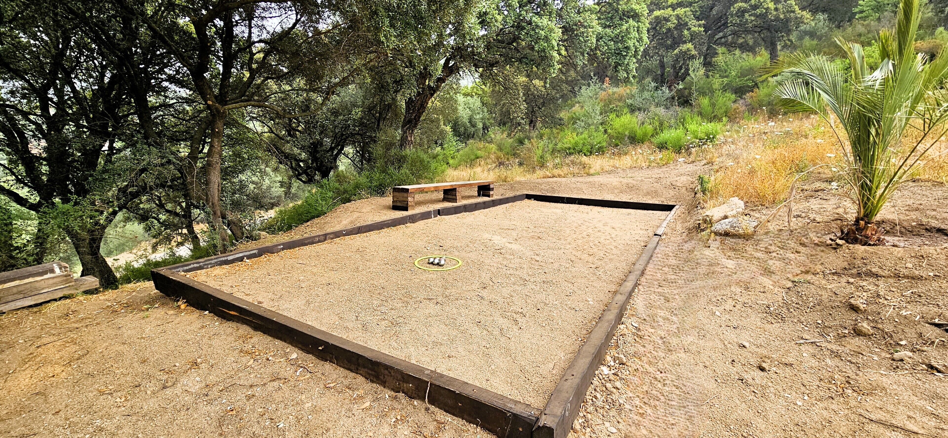 A sandy area with a wooden bench and a circular green target.