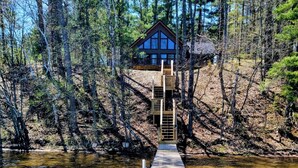 A wooden dock leading to a cabin surrounded by trees. - Make Memories In This Top Notch Lakefront Cabin (Stone Lake)