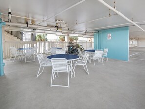 A covered outdoor seating area with tables and chairs, a staircase, and a blue wall.