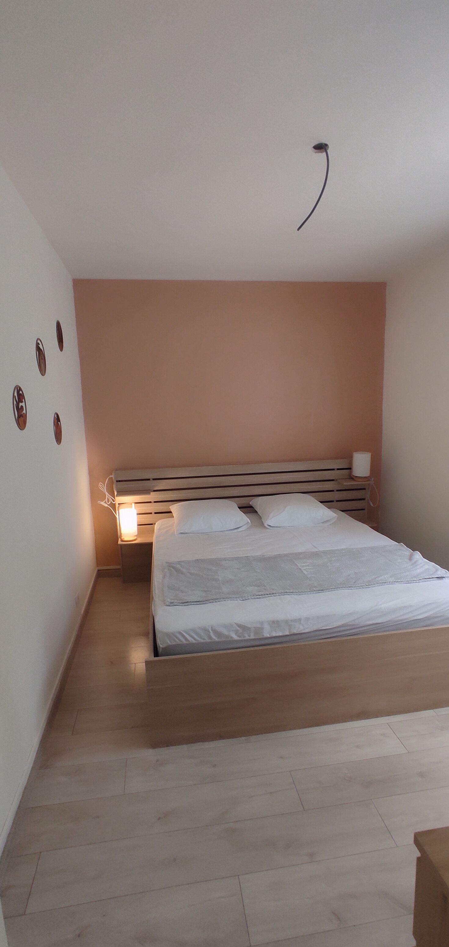 Ein Schlafzimmer mit einem Bett, einer Nachttischlampe und einer Wandleuchte.