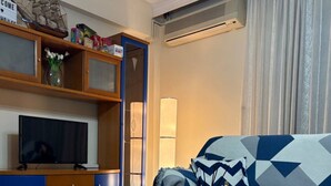 Una sala de estar moderna con sofá, mesa de centro, televisor y estantería.