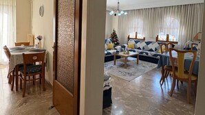 Amplia sala de estar con comedor, un amplio sofá y una araña.