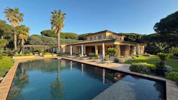 A large, two-story house with a swimming pool in the foreground.