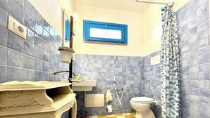 Et badeværelse med et ternet gulv, en vask, et toilet og en bruseniche.