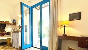 Et værelse med et ternet gulv, en dør med blå ramme der fører ud, et bord med en lampe og en stol.