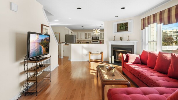 A living room with a red sofa, a TV on a stand, a fireplace, and a kitchen in the background.