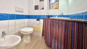 A bathroom with a toilet, bidet, sink, and a mirror. - "Le Corti Sarde Sea Breeze" (Bari Sardo)