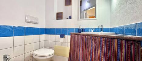 Un baño con inodoro, bidé, lavamanos y espejo.