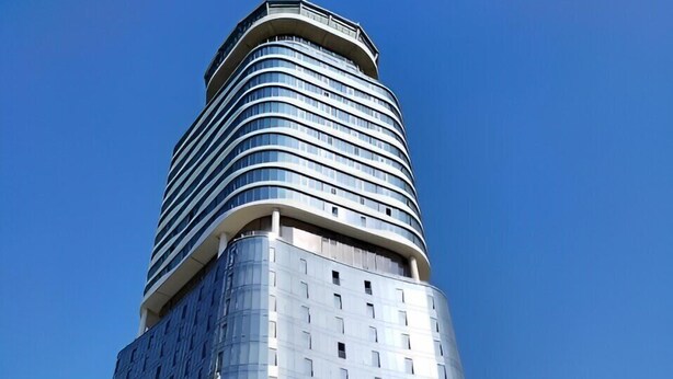 Un edifici alt, modern, amb una part superior corbada i façana de vidre.
