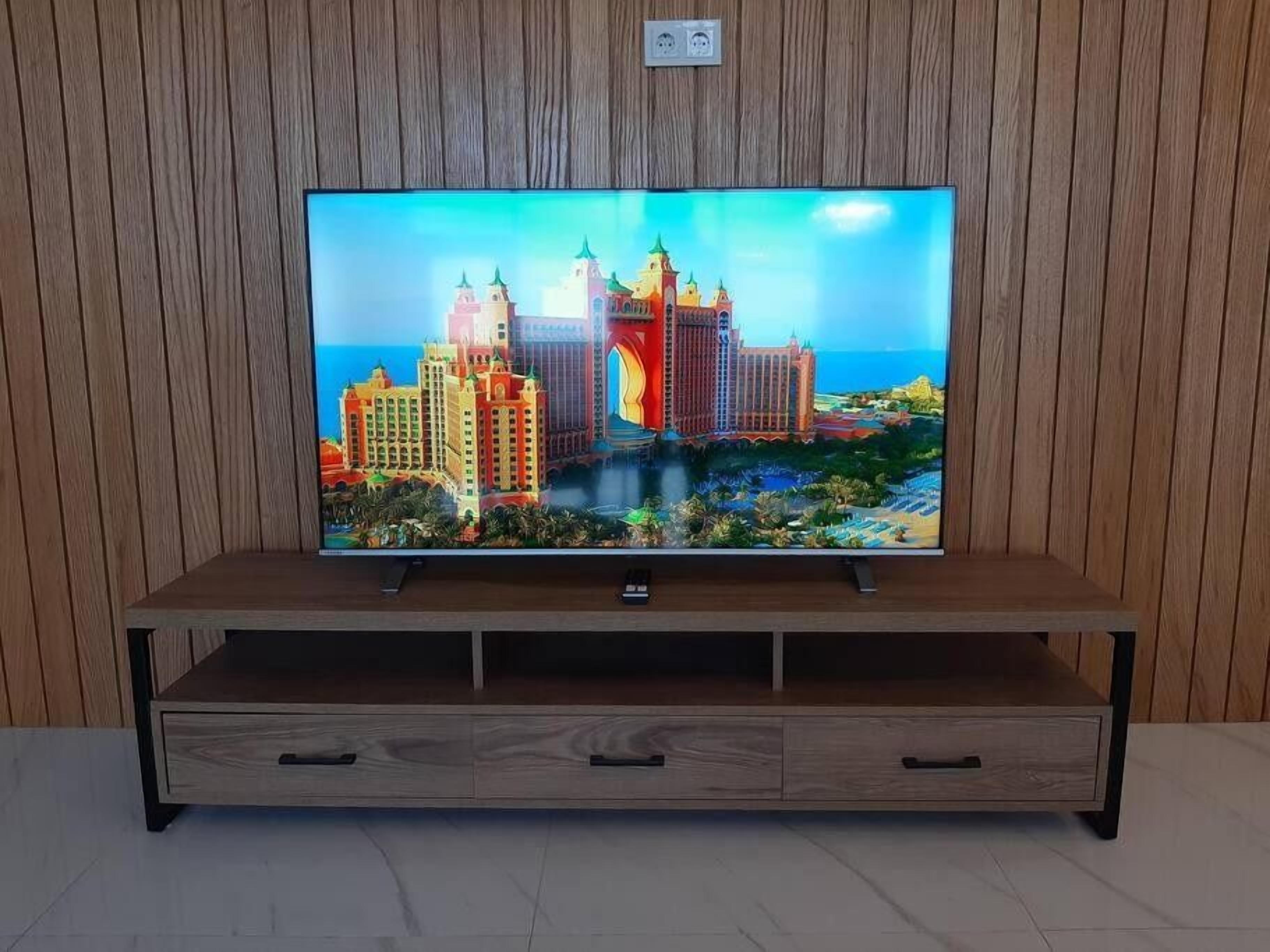 Un téléviseur posé sur un meuble en bois muni de trois tiroirs.