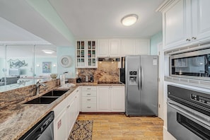 A modern kitchen with white cabinets, stainless steel appliances, and a granite countertop.