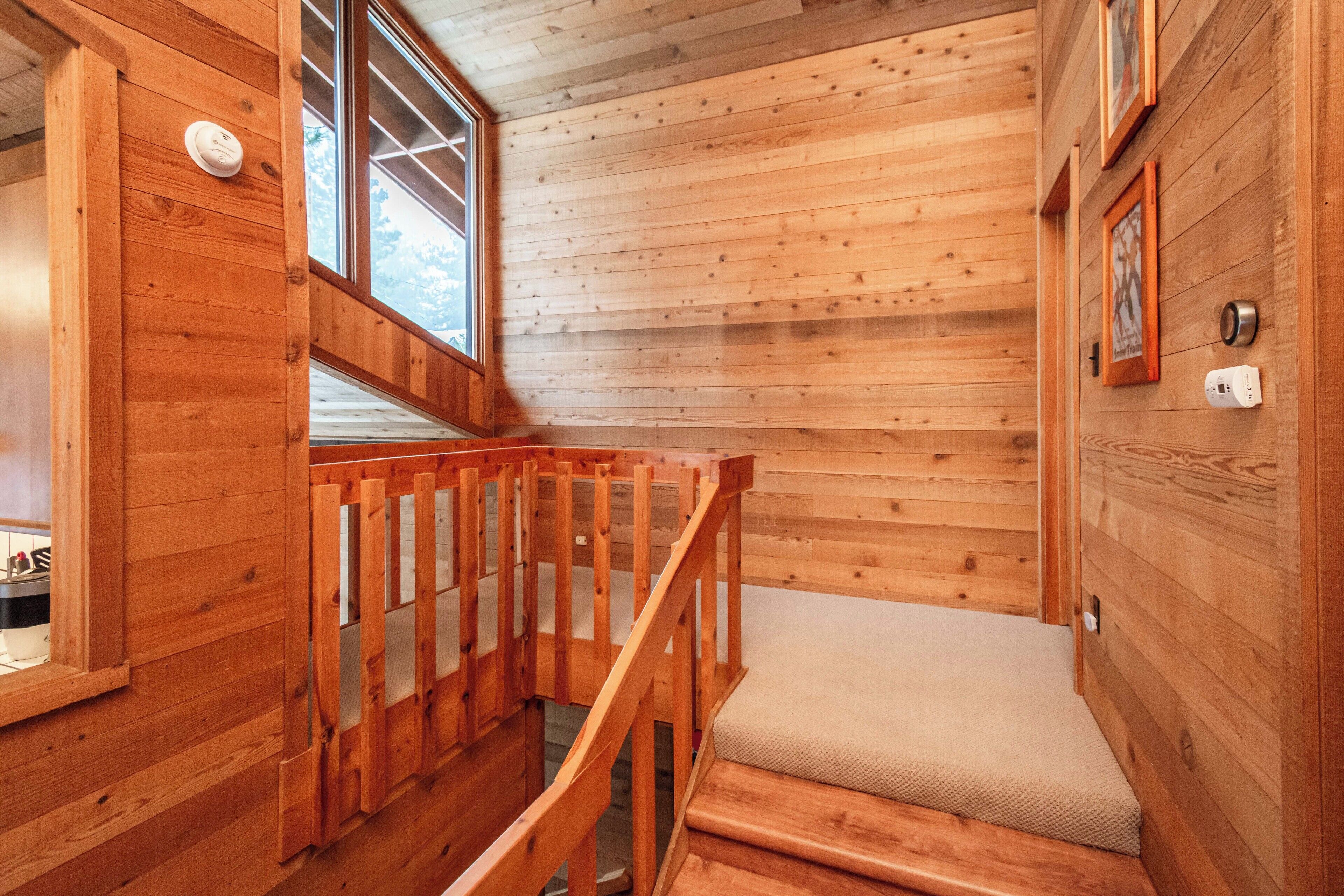 A wooden interior with a staircase leading to a lower level, a window, and a wall-mounted device.