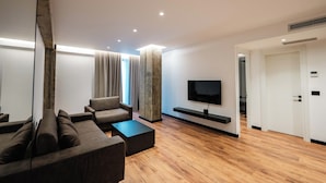 A modern living room with a sofa, coffee table, and TV. - Cuni Luxury Hotel (Sarandë)