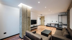 A modern living room with a large TV, a sofa, a coffee table, and a wooden floor. - Cuni Luxury Hotel (Sarandë)