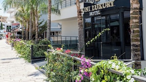 A hotel with a modern facade, palm trees, and a paved walkway. - Cuni Luxury Hotel (Sarandë)