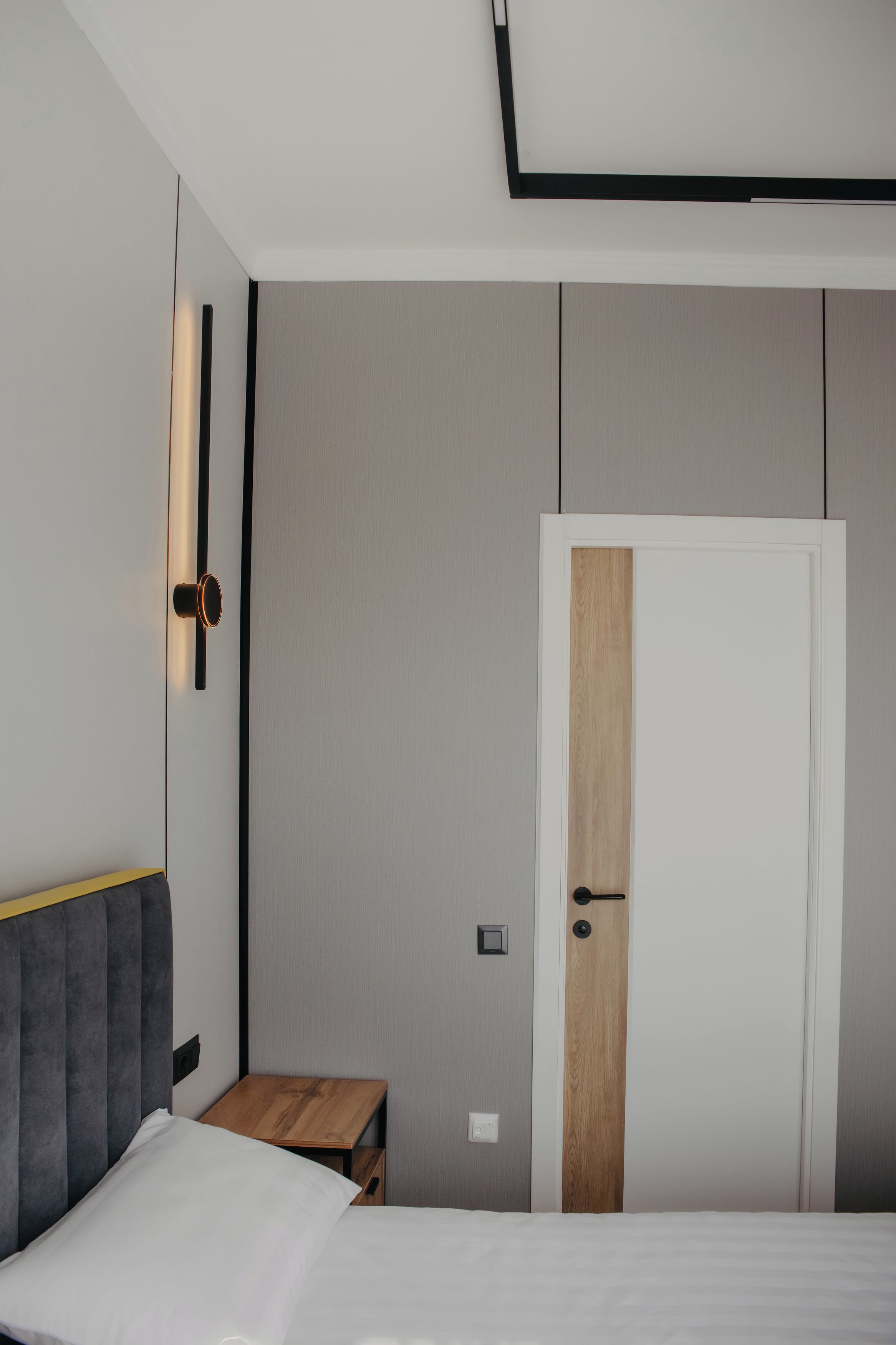 A modern bedroom with a bed, bedside table, and a wardrobe with a wooden panel.