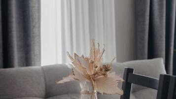 Una mesa de comedor con un florero de flores secas, una cafetera y recipientes con nueces y granos de café.