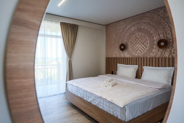 A modern bedroom with a wooden headboard, a large bed with white linens, and a patterned wall design.